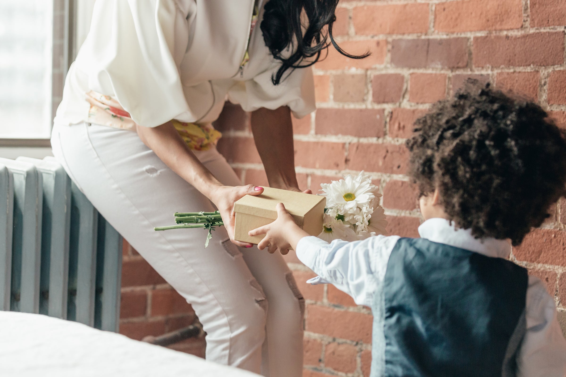 Junge gibt Mutter ein Geschenk und Blumen