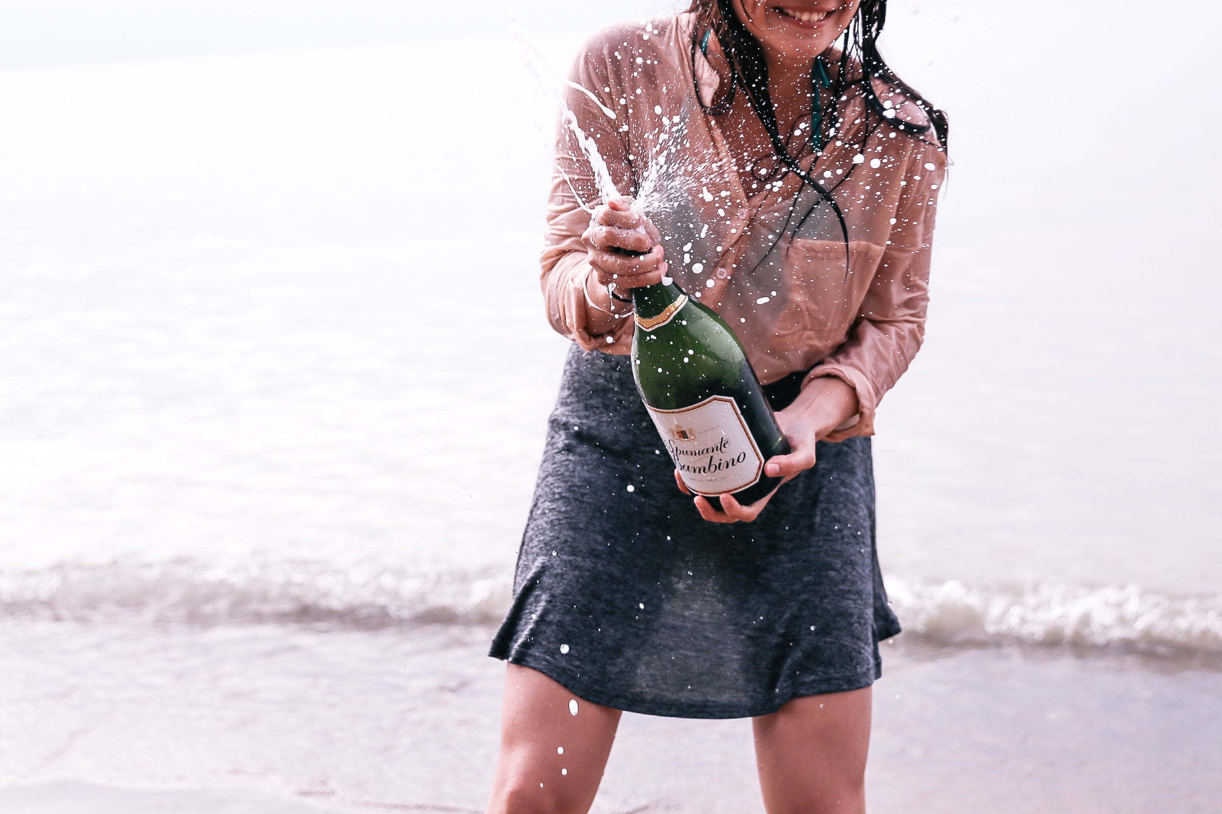 Wet woman at the beach with champagne